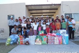 Miembros del grupo acompañados por los niños y directivos de la Casa Hogar y los regalos